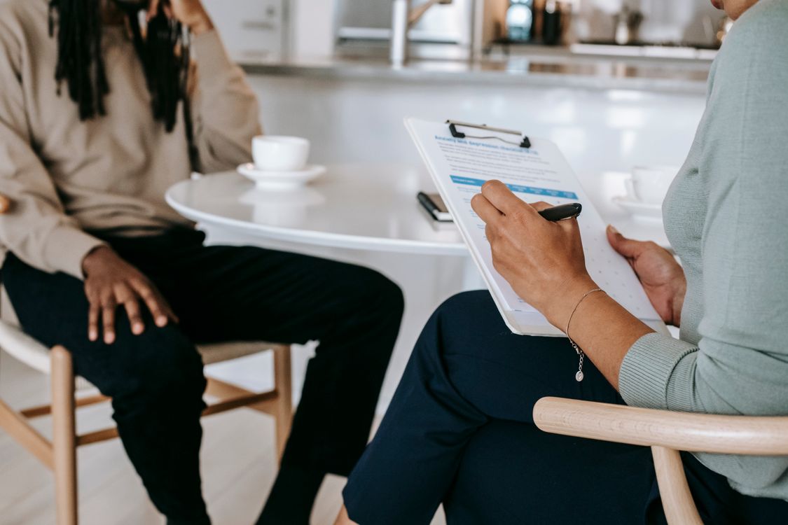 Illustrative stock photograph of a counsellor taking notes during a conversation